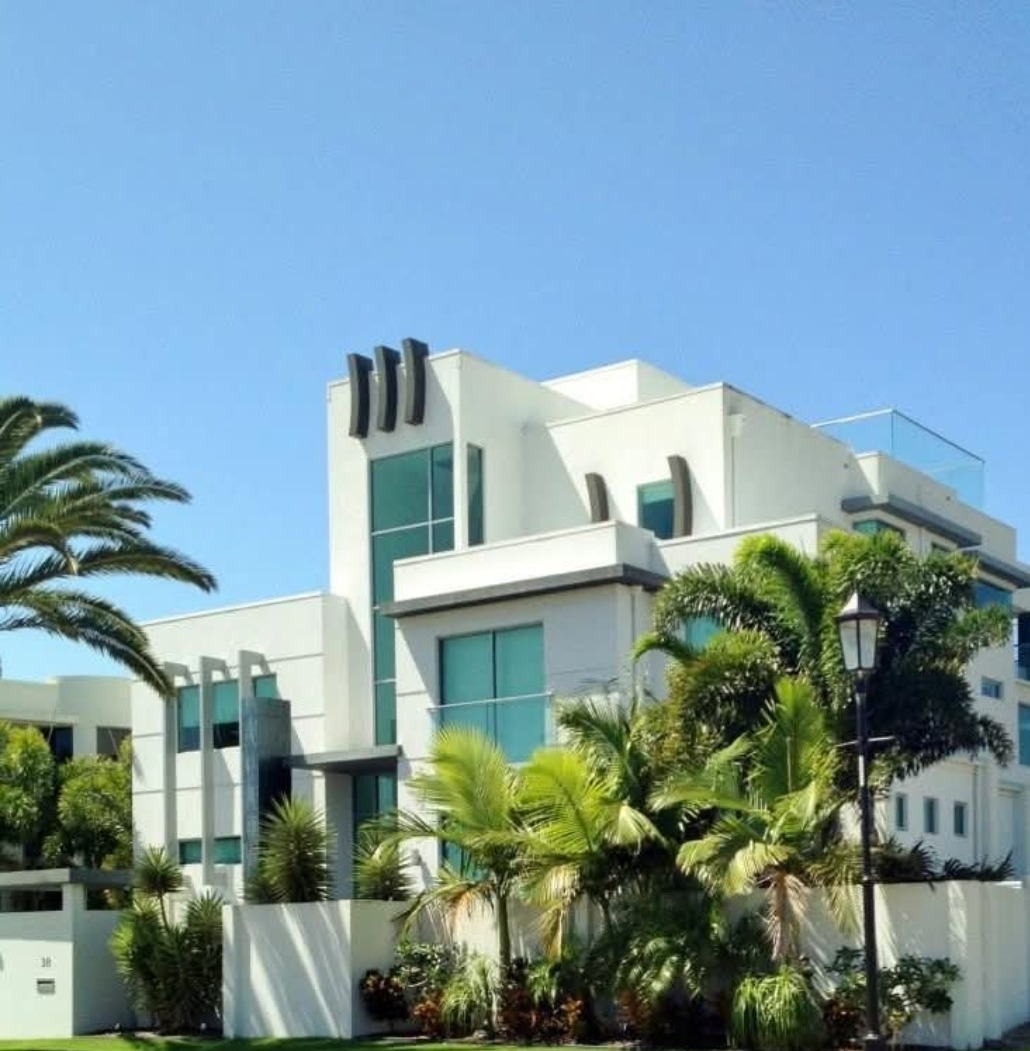A large white Gold Coast home with palm trees, freshly painted